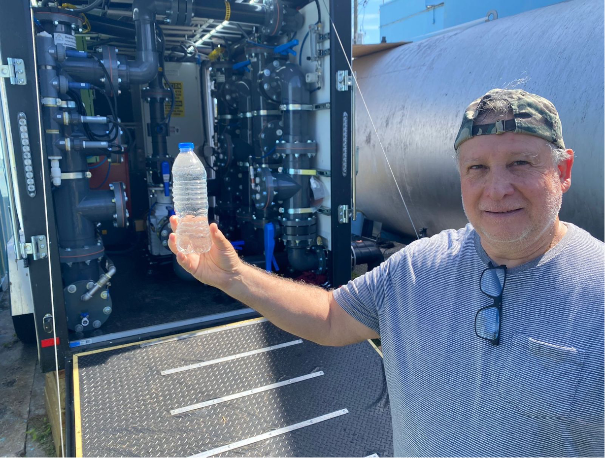 Operator holding a treated-water sample beside the CF21S manifold